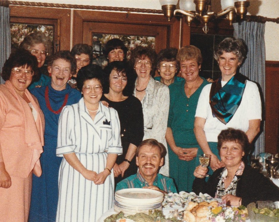 Group shot with Ray kneeling among colleagues at house party